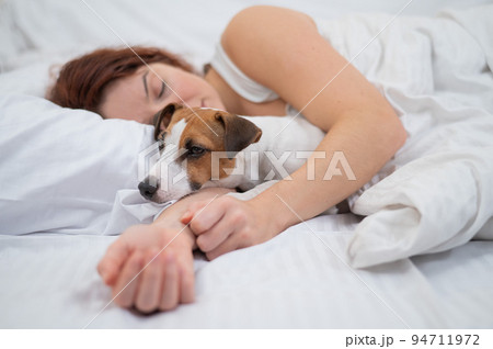 Caucasian woman is napping in bed hugging her beloved dog. Caucasian woman is napping in bed hugging her beloved dog. 94711972