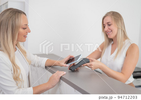 A woman pays using a non -contact payment of the NFC used by a smartphone. A woman pays using a non -contact payment of the NFC used by a smartphone. 94712203