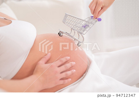 Faceless pregnant woman with shopping cart on her belly. Faceless pregnant woman with shopping cart on her belly. 94712347