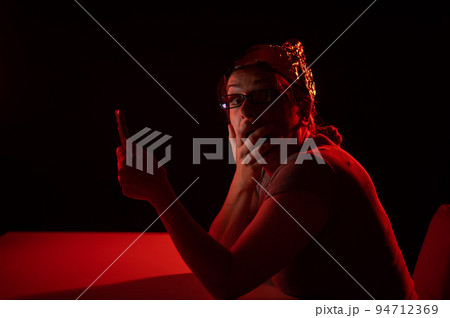 Paranoid caucasian woman using smartphone wearing tinfoil hat. Conspiracy theory. Paranoid caucasian woman using smartphone wearing tinfoil hat. Conspiracy theory. 94712369