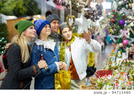 Friendly family chooses Christmas souvenirs and toys Friendly family chooses Christmas souvenirs and toys 94713480