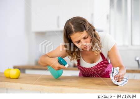 Young woman cleaning kitchen countertop at home Young woman cleaning kitchen countertop at home 94713694