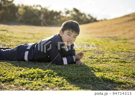 芝生に寝転ぶ男子 94714313