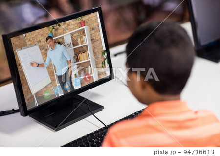 Mixed race schoolboy using computer on video call with male teacher Mixed race schoolboy using computer on video call with male teacher 94716613