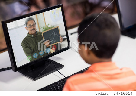 Mixed race schoolboy using computer on video call with male teacher Mixed race schoolboy using computer on video call with male teacher 94716614