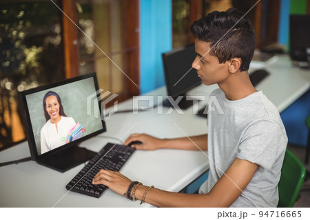 Mixed race schoolboy using computer on video call with female teacher Mixed race schoolboy using computer on video call with female teacher 94716665