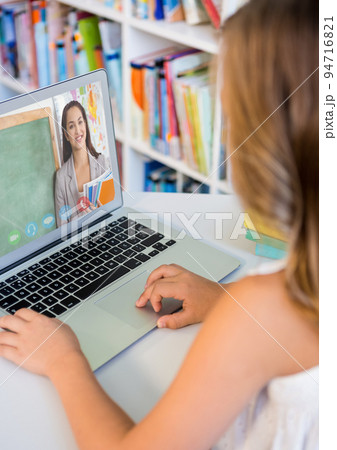 Caucasian schoolgirl using laptop on video call with female teacher 94716821
