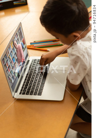 Mixed race schoolboy using laptop on video call with male teacher Mixed race schoolboy using laptop on video call with male teacher 94716834