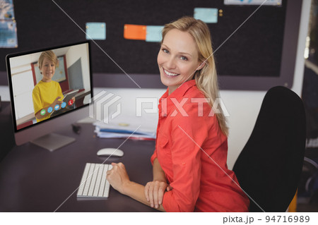 Portrait of smiling caucasian female teacher using computer on video call with schoolboy 94716989