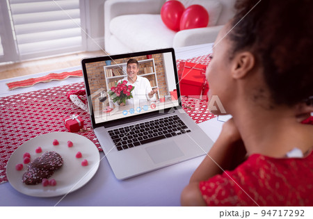 Diverse couple making valentines date video call the man on laptop screen holding flowers Diverse couple making valentines date video call the man on laptop screen holding flowers 94717292