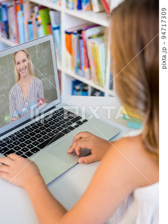 Caucasian schoolgirl using laptop on video call with female teacher 94717309