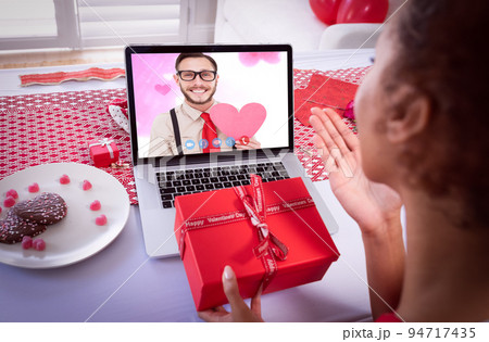 Diverse couple making valentines date video call the woman blowing kiss to man on laptop screen Diverse couple making valentines date video call the woman blowing kiss to man on laptop screen 94717435