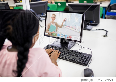 Mixed race schoolgirl using computer on video call with female teacher Mixed race schoolgirl using computer on video call with female teacher 94717454