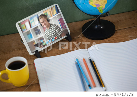 Caucasian schoolboy learning on tablet screen on desk during video call Caucasian schoolboy learning on tablet screen on desk during video call 94717578