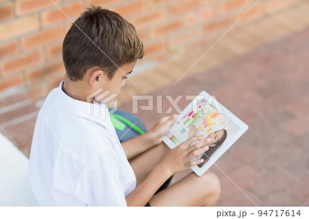 Male caucasian student having a video call with female teacher on digital tablet at school 94717614