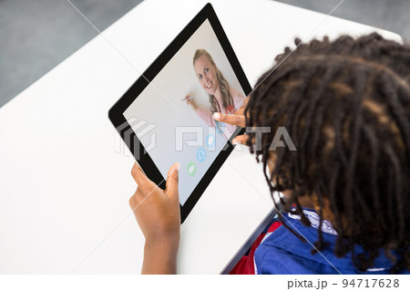 Male student having a video call with female teacher on digital tablet at school 94717628