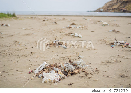 Spilled garbage on the beach. Empty used dirty plastic bottles. Environmental pollution. Ecological problem Spilled garbage on the beach. Empty used dirty plastic bottles. Environmental pollution. Ecological problem 94721239