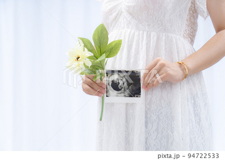 マタニティドレスでエコー写真を持つ妊婦 白背景（本物の臨月妊婦さんを撮影） 94722533
