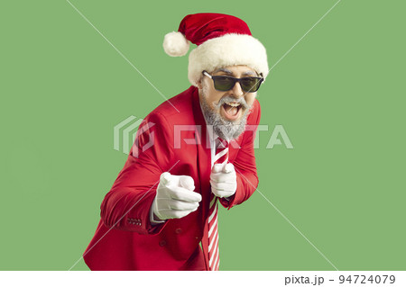 Happy funny man in red suit, Christmas hat and cool sunglasses points finger at you Happy funny man in red suit, Christmas hat and cool sunglasses points finger at you 94724079
