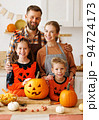 Happy family looking at camera while make jack-o-lantern from pumpkin, getting ready for halloween 94724173