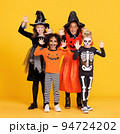 Happy Halloween. Kids in carnival costumes and makeup make a terrible gesture on bright colored yellow background 94724202