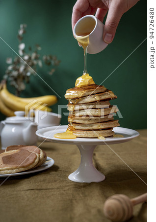Pancakes stack with butter and honey. Delicious homemade pancakes, colorful green background. 94726480