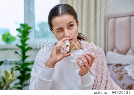 Teenage girl with runny nose treating rhinitis using nose drops spray Teenage girl with runny nose treating rhinitis using nose drops spray 94726589
