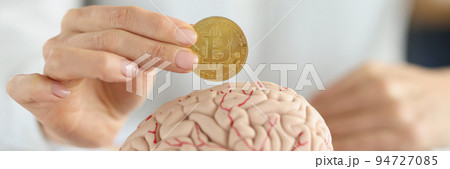 Businesswoman holding bitcoin coin in front of human brain Businesswoman holding bitcoin coin in front of human brain 94727085
