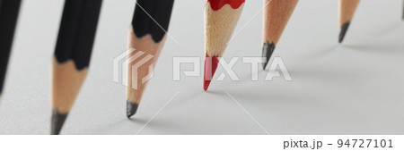 Tips of group of pencils put on paper in strict order, red among black pens Tips of group of pencils put on paper in strict order, red among black pens 94727101