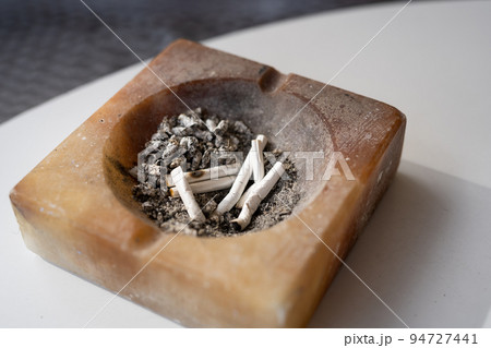 Ashtray on the table with cigarettes and ashes close-up. Ashtray on the table with cigarettes and ashes close-up. 94727441