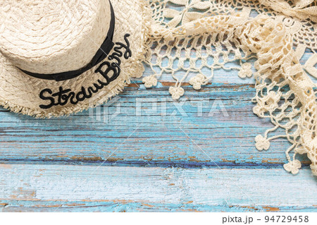 A straw hat and a white knitting scarf on the light blue wooden background. Beach and Summer concept. A straw hat and a white knitting scarf on the light blue wooden background. Beach and Summer concept. 94729458