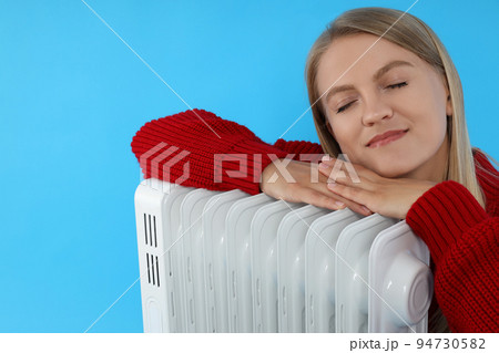 Heating season, woman with heater on blue background Heating season, woman with heater on blue background 94730582