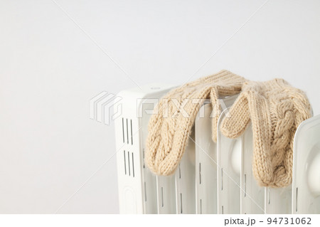 Concept of heating season, modern electric heater with mittens Concept of heating season, modern electric heater with mittens 94731062