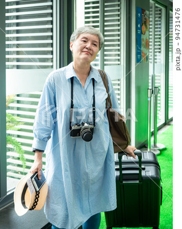 Portrait of senior adult elderly asian woman 60s smiling standing with suitcase luggage bag and camera for travel concept. 94731476
