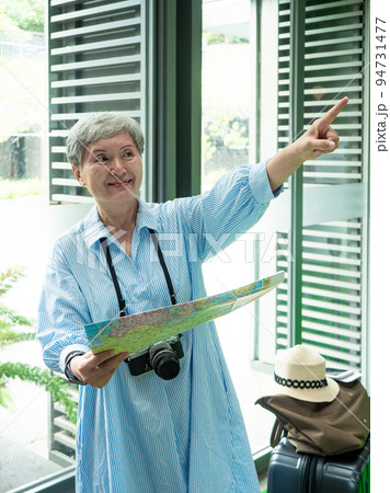 Portrait of mature aged asian woman 60s holding a map in concept of tourism to travel, Travel or exploring concept. Portrait of mature aged asian woman 60s holding a map in concept of tourism to travel, Travel or exploring concept. 94731477