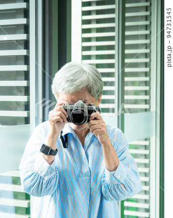 Portrait of happy senior adult elderly asia woman 60s taking pictures with photo camera for travel concept. 94731545