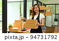 Attractive woman entrepreneur wearing apron holding cardboard and smiling to camera. Online selling, E-commerce concept 94731792