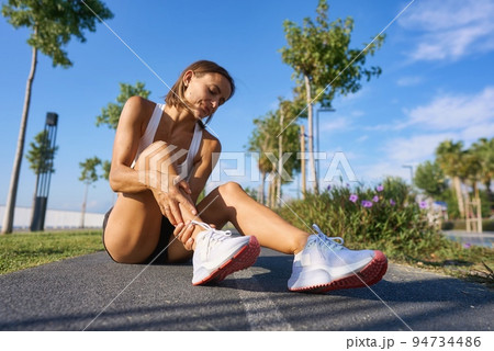 runner with ankle injury holds foot to reduce pain. running problem for athlete training outdoors 94734486