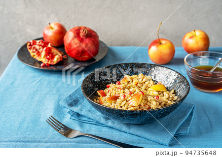Sweet homemade barley porridge with pomegranate seeds, apples and honey. Rosh Hashanah celebration 94735648