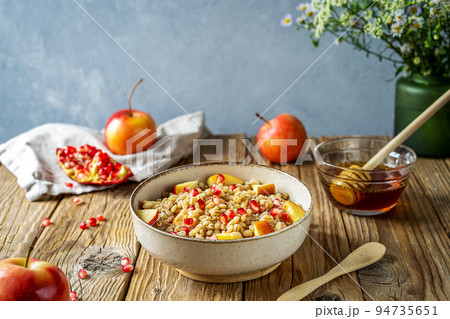Sweet homemade barley porridge with pomegranate seeds, apples and honey. Rosh Hashanah celebration Sweet homemade barley porridge with pomegranate seeds, apples and honey. Rosh Hashanah celebration 94735651