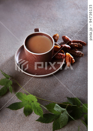 A cup of coffee and a pastille. The pastille is rolled into a roll. A branch with leaves. Healthy food without sugar.Vertical photo. A cup of coffee and a pastille. The pastille is rolled into a roll. A branch with leaves. Healthy food without sugar.Vertical photo. 94736135
