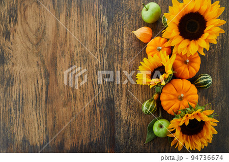 Pumpkin and sunflowers over old wooden background with copy space. Autumn background decoration. 94736674