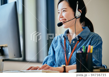 オフィスで電話対応をする若い女性 オフィスで電話対応をする若い女性 94736735