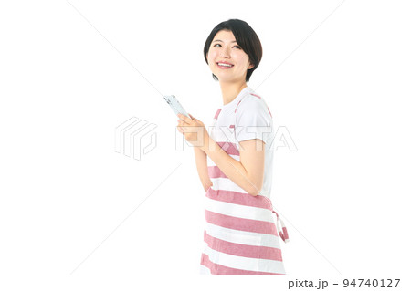 スマホを操作するエプロン姿の若い主婦（白バック） 94740127
