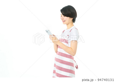 スマホを操作するエプロン姿の若い主婦(白バック) スマホを操作するエプロン姿の若い主婦(白バック) 94740131