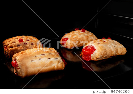 Four baked homemade buns with red strawberry jam in electric oven Four baked homemade buns with red strawberry jam in electric oven 94740206