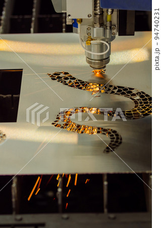 CNC laser cutting machine making holes in sheet metal with sparks 94740231