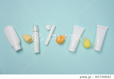 White plastic tubes for cream, gel and other cosmetics and sponges on a blue background White plastic tubes for cream, gel and other cosmetics and sponges on a blue background 94740692