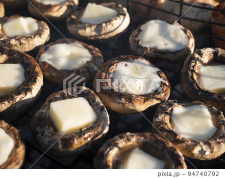 Cheese stuffed mushrooms. Grilled champignons filled with cheese. Hot portobello cups with melted mozzarella on the grill grate Cheese stuffed mushrooms. Grilled champignons filled with cheese. Hot portobello cups with melted mozzarella on the grill grate 94740792