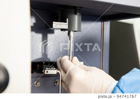 Scientist loading a test tube containing a patient sample on the  flow cytometer for analysis. Flow cytometer 94741767